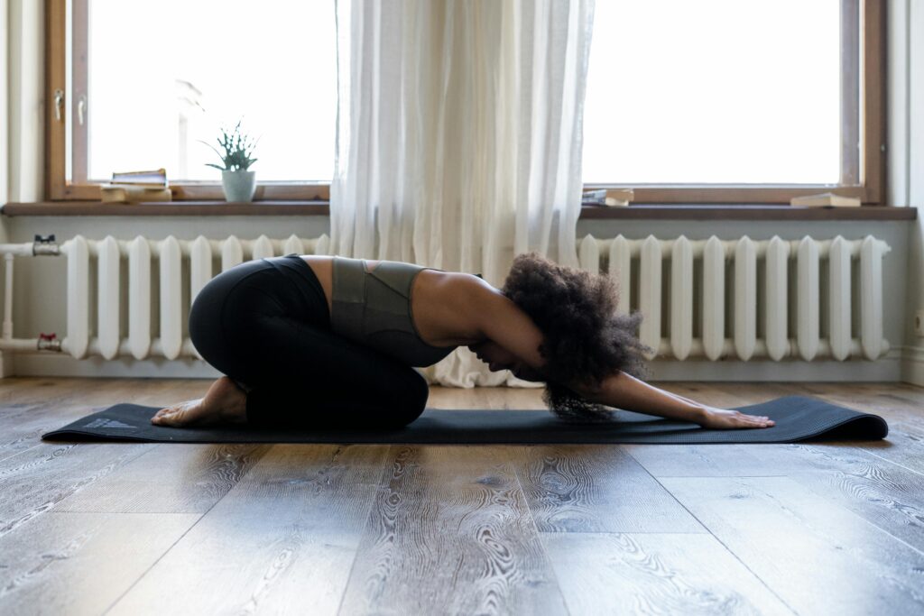 Woman practicing yoga at home on a mat in a cozy room. Embracing fitness and wellness indoors.