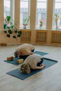 Two adults practicing yoga in a serene indoor setting, focusing on relaxation and wellness.