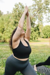 Plus size woman in yoga pose outdoors promoting fitness and healthy living.