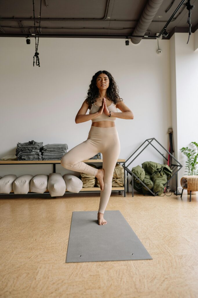 Woman performing a yoga pose indoors, showcasing wellness and balance in a serene studio environment.